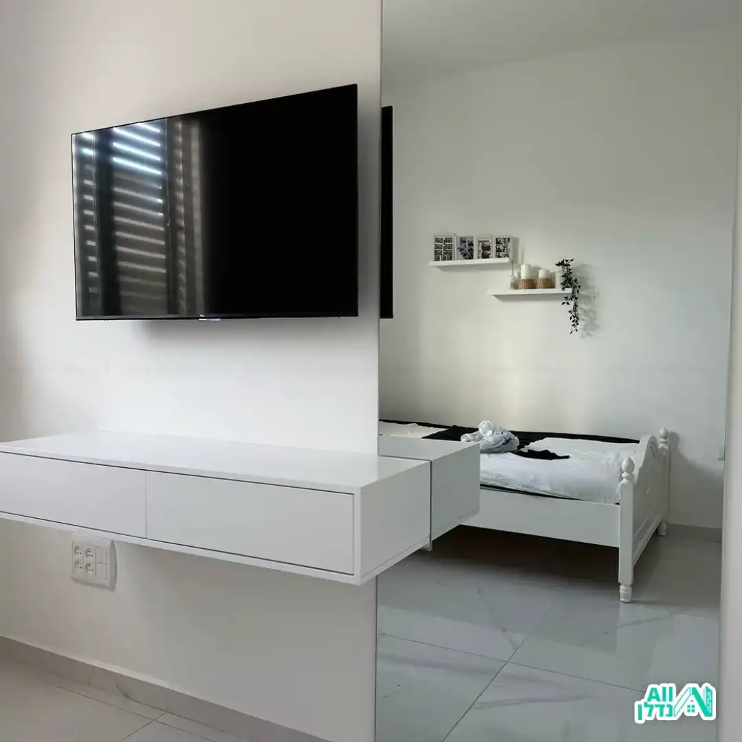 שיפוץ קיר בחדר שינה עם טלוויזיה ומראה שעליה מוצמדת שידה צפה