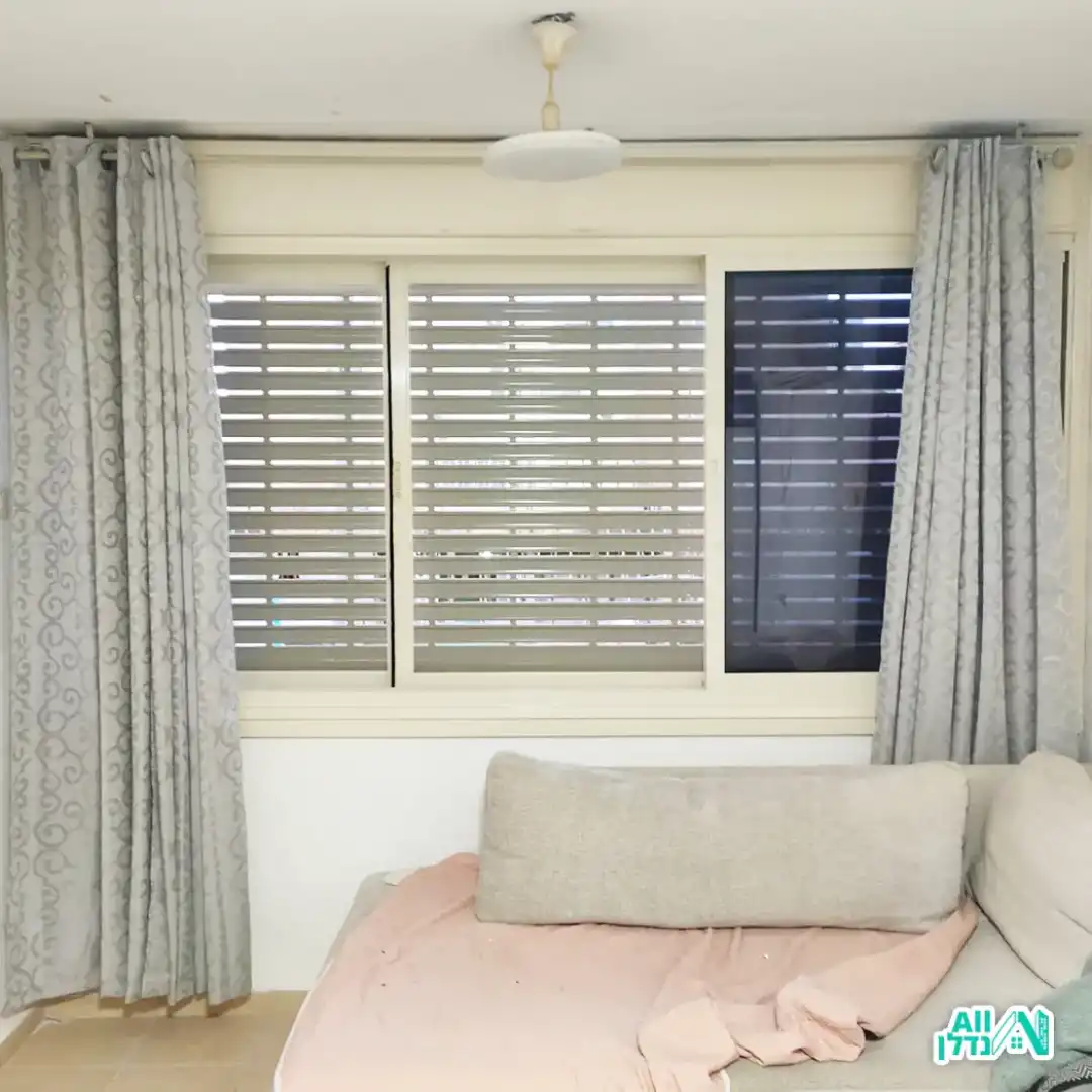 דלת אלומיניום לבנה מעוצבת בצורה ייחודית בפתח שהוא חצי עיגול