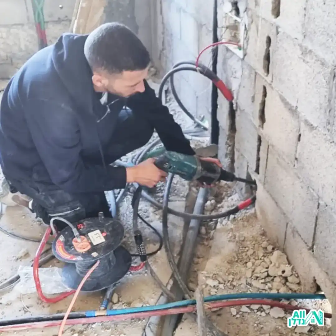 בעל מקצוע קודח בקיר להתקנת קווי אינסטלציה