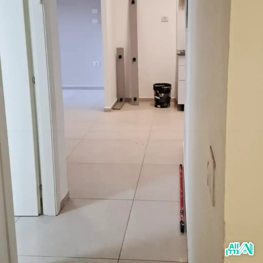 קיר צבוע לידו דלי צבע ומקל ששימש לצביעה